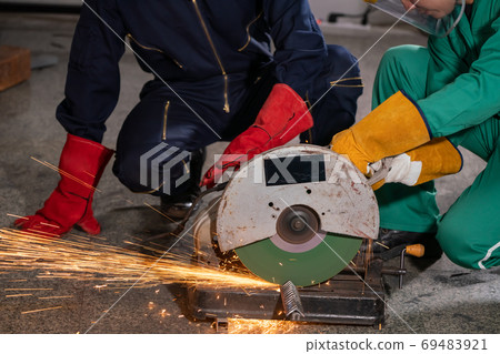 Professional mechanic man is cutting steel metal with rotating carbon blade 69483921
