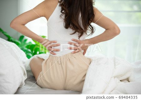 woman have a back pain sitting on bed in bedroom feeling painful,Healthcare concept woman have a back pain sitting on bed in bedroom feeling painful,Healthcare concept 69484335