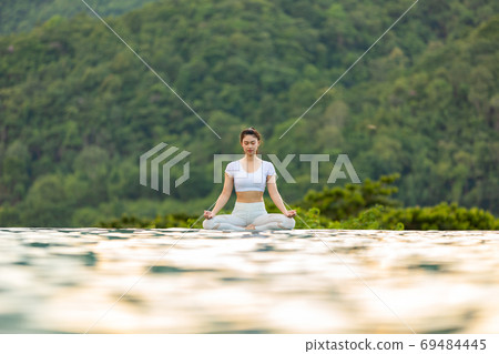Calm of Beautiful Attractive Asian woman practice yoga Lotus pose on the pool above Mountain peak 69484445