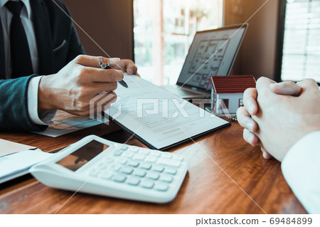 Agents are using pens pointing to contracts and are being explai 69484899