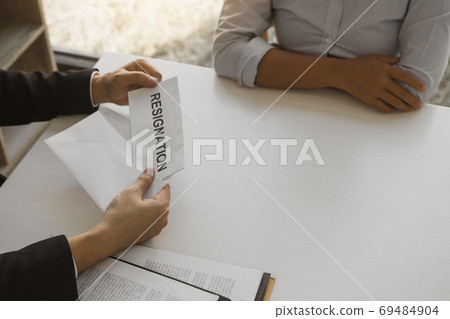 Woman employee takes the handle to the resignation envelope whil 69484904