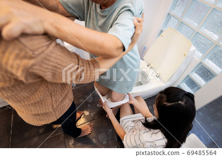 Family taking care,help, support of elderly patient with giving adult diaper change,asian senior woman suffer from Stress Urinary Incontinence,old people putting nappy with bladder control problem Family taking care,help, support of elderly patient with giving adult diaper change,asian senior woman suffer from Stress Urinary Incontinence,old people putting nappy with bladder control problem 69485564