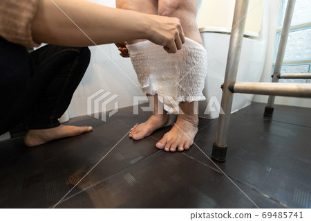 Caring female nurse assisting a elderly patient with giving diaper change,asian senior woman put nappy,disposable diaper,disabled old people with bladder control problem,stress urinary incontinence  69485741