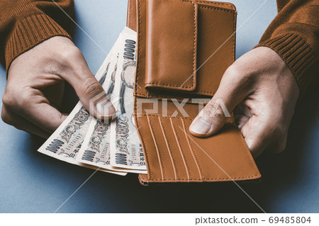 A man who puts money out of his wallet 69485804