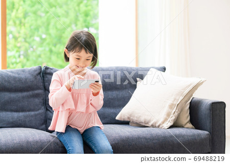A girl playing on a smartphone A girl playing on a smartphone 69488219