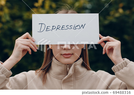 Woman holding white sheet paper labeled word Depression in hand. Woman holding white sheet paper labeled word Depression in hand. 69488316