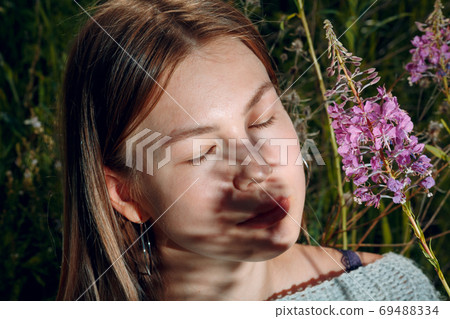 Pretty young woman outdoor in the park with summer flowers Pretty young woman outdoor in the park with summer flowers 69488334