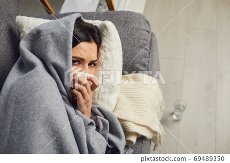 Above view of young girl lying on sofa, covered with warm plaid, suffering from bad cold or infection at home 69489350