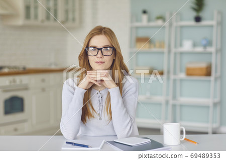 Positive woman looking at camera and listening to somebody during videocall or teleconference online Positive woman looking at camera and listening to somebody during videocall or teleconference online 69489353