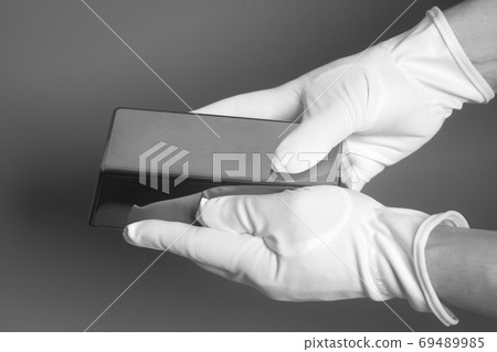 Men's hand in white gloves holding a silver bullion Men's hand in white gloves holding a silver bullion 69489985