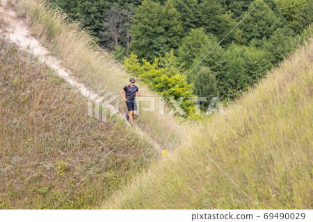 Young man running downhill in nature park Young man running downhill in nature park 69490029