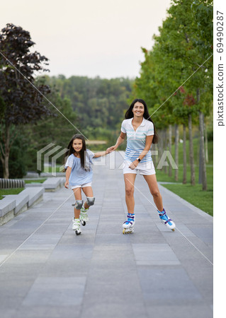 mother and her little daughter rollerskating 69490287