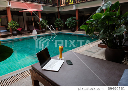 A laptop, mobile and mango smoothie on a sunbed 69490561