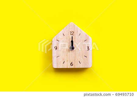 Miniature house wooden clock on yellow background. Miniature house wooden clock on yellow background. 69493710