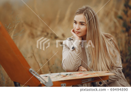 Woman in a brown coat painting in a field Woman in a brown coat painting in a field 69494890
