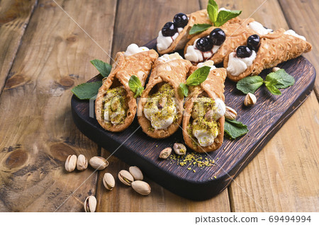 Cannoli Sicily. Traditional Italian sweet with ricotta and various fillings. Food on a wooden 69494994