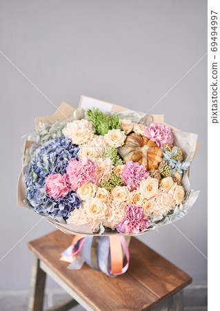 Autumn bouquet of mixed flowers on wooden table. The work of the florist at a flower shop. Fresh cut flower. Autumn bouquet of mixed flowers on wooden table. The work of the florist at a flower shop. Fresh cut flower. 69494997