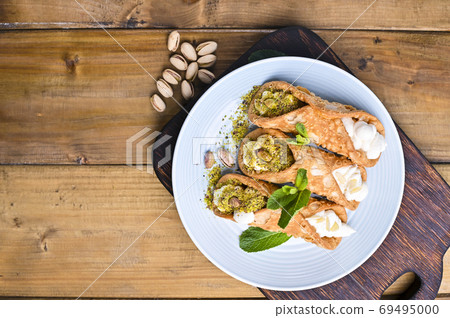 Cannoli Sicily. Traditional Italian sweet with ricotta and various fillings. Food on a wooden 69495000