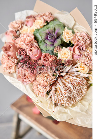 Autumn bouquet of mixed flowers with Protea and Brassica on wooden table. The work of the florist at a flower shop. Fresh cut flower. Autumn bouquet of mixed flowers with Protea and Brassica on wooden table. The work of the florist at a flower shop. Fresh cut flower. 69495012