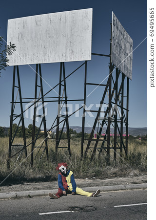 scary evil clown sitting on the ground 69495665