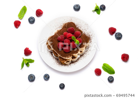 portion of Classic tiramisu dessert with raspberries and blueberries on ceramic plate isolated on white portion of Classic tiramisu dessert with raspberries and blueberries on ceramic plate isolated on white 69495744