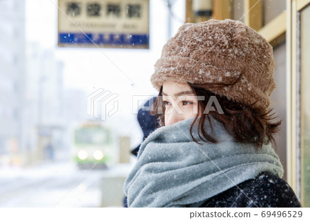 A traveler woman waiting for a train at a snowy station 69496529