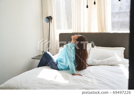 Female with her eyes closed relaxing in a bedroom 69497226