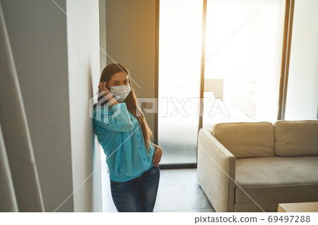 Woman with long dark hair leaning against the wall Woman with long dark hair leaning against the wall 69497288