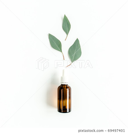 Bottle of eucalyptus essential oil, eucalyptus leaves on white background. Natural Organic cosmetics products. Flat lay, top view. Bottle of eucalyptus essential oil, eucalyptus leaves on white background. Natural Organic cosmetics products. Flat lay, top view. 69497401