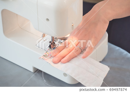 Female hand sewing a mask with a sewing machine Female hand sewing a mask with a sewing machine 69497874