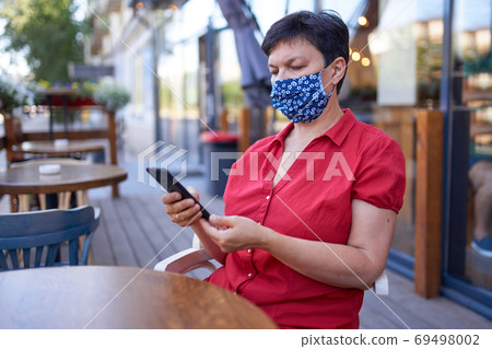 Beautiful mature woman with with dark hair in a handmade protective mask 69498002