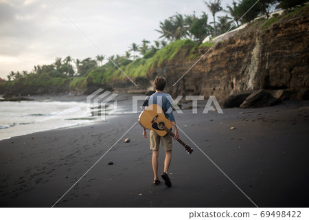 Romantic young man with a guitar on the beach Romantic young man with a guitar on the beach 69498422