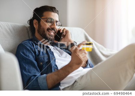 Online Banking. Handsome Western Guy Using Cellphone And Credit Card At Home 69498464