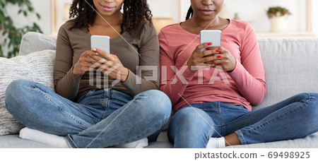 Unrecognizable black ladies using mobile phones at home 69498925