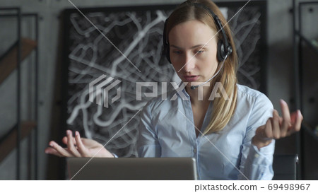 Happy female manager wearing wireless headphones, looking at laptop screen, holding pleasant conversation with partners clients online, working remotely at workplace Happy female manager wearing wireless headphones, looking at laptop screen, holding pleasant conversation with partners clients online, working remotely at workplace 69498967