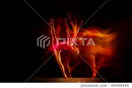 Young flexible female gymnast isolated on black studio background in mixed light, 69499440