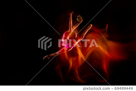 Young flexible female gymnast isolated on black studio background in mixed light, 69499449