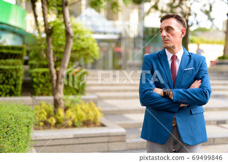 Mature handsome Italian businessman relaxing outside of the building Mature handsome Italian businessman relaxing outside of the building 69499846