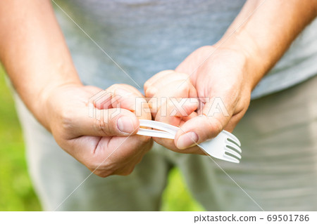 Male hand breaks plastic disposable fork 69501786