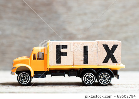Truck hold letter block in word fix on wood background 69502794
