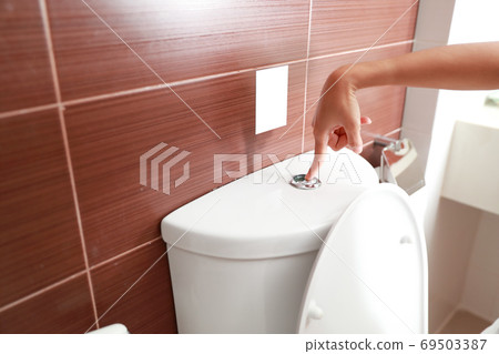 woman hand flush toilet after using 69503387