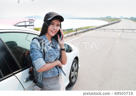 Young asian traveler with car using smart phone while traveling during holiday vacation. Young asian traveler with car using smart phone while traveling during holiday vacation. 69503719