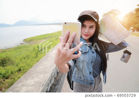 Young asian traveler using smart phone and do self portrait while traveling during holiday vacation. Young asian traveler using smart phone and do self portrait while traveling during holiday vacation. 69503729