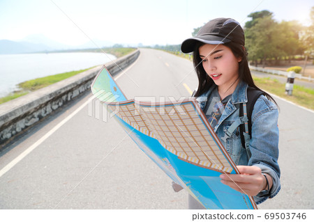 Young asian traveler searching direction on location map while traveling during holiday vacation. Young asian traveler searching direction on location map while traveling during holiday vacation. 69503746