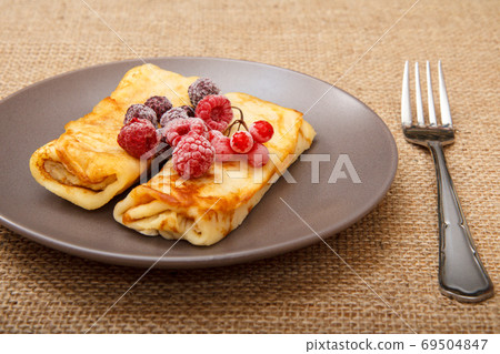 Homemade pancakes filled with cottage cheese and topped with frozen raspberries Homemade pancakes filled with cottage cheese and topped with frozen raspberries 69504847