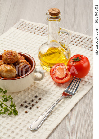 Fried meat cutlets in ceramic soup bowl, red tomatoes and sunflower oil Fried meat cutlets in ceramic soup bowl, red tomatoes and sunflower oil 69504902