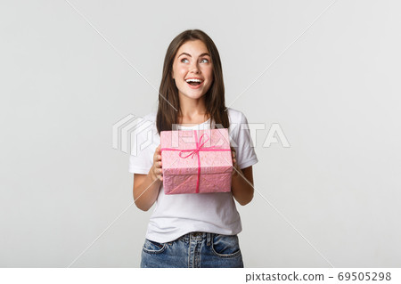 Surprised happy birthday girl receiving wrapped gift, white background Surprised happy birthday girl receiving wrapped gift, white background 69505298