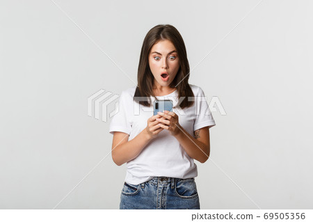 Shocked and impressed brunette girl looking amazed at smartphone screen 69505356
