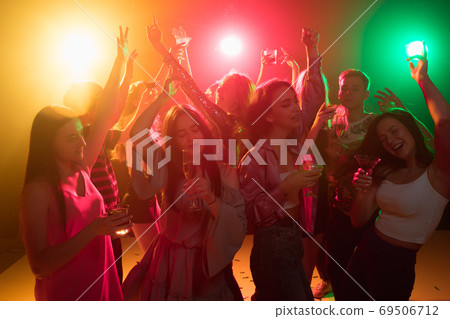 A crowd of people in silhouette raises their hands on dancefloor on neon light background A crowd of people in silhouette raises their hands on dancefloor on neon light background 69506712