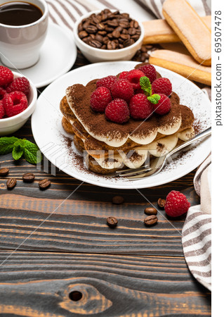 portion of Classic tiramisu dessert with raspberries, savoiardi cookies and cup of espresso coffee isolated on wooden background portion of Classic tiramisu dessert with raspberries, savoiardi cookies and cup of espresso coffee isolated on wooden background 69507478